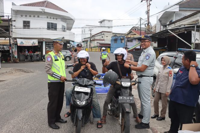 
 Satlantas Polres Bangka Barat membagikan helm gratis kepada pengendara yang melintas di Jalan Raya Pasar Mentok, Bangka Barat pada kegiatan operasi keselamatan menumbing 2026, Jumat 13 Februari 2026. (Foto: babeltimes.co/Ho-Humas Polres Babar)